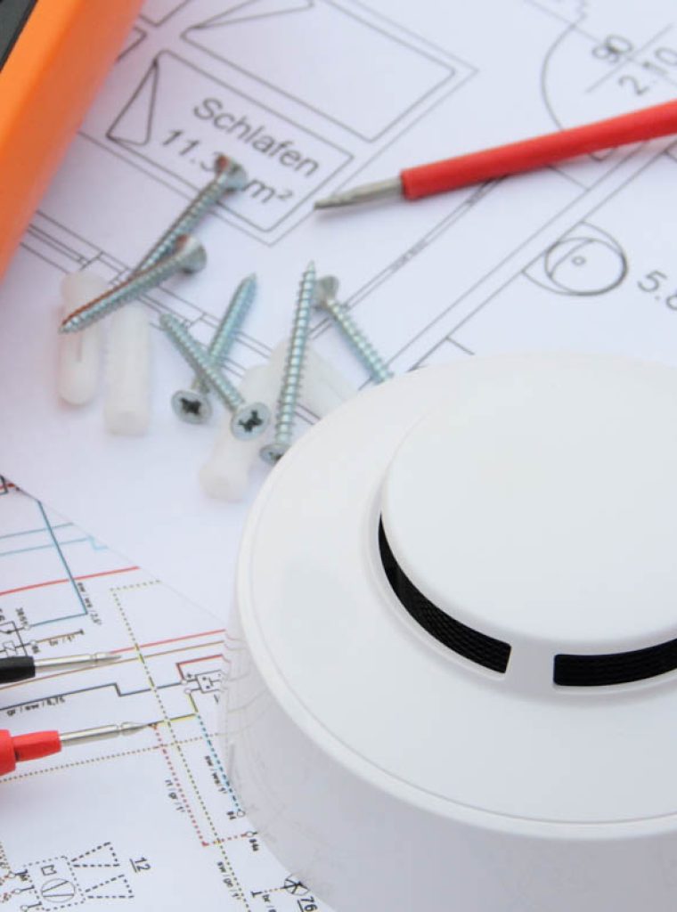 smoke detector with a screwdriver and a measuring device on a ci